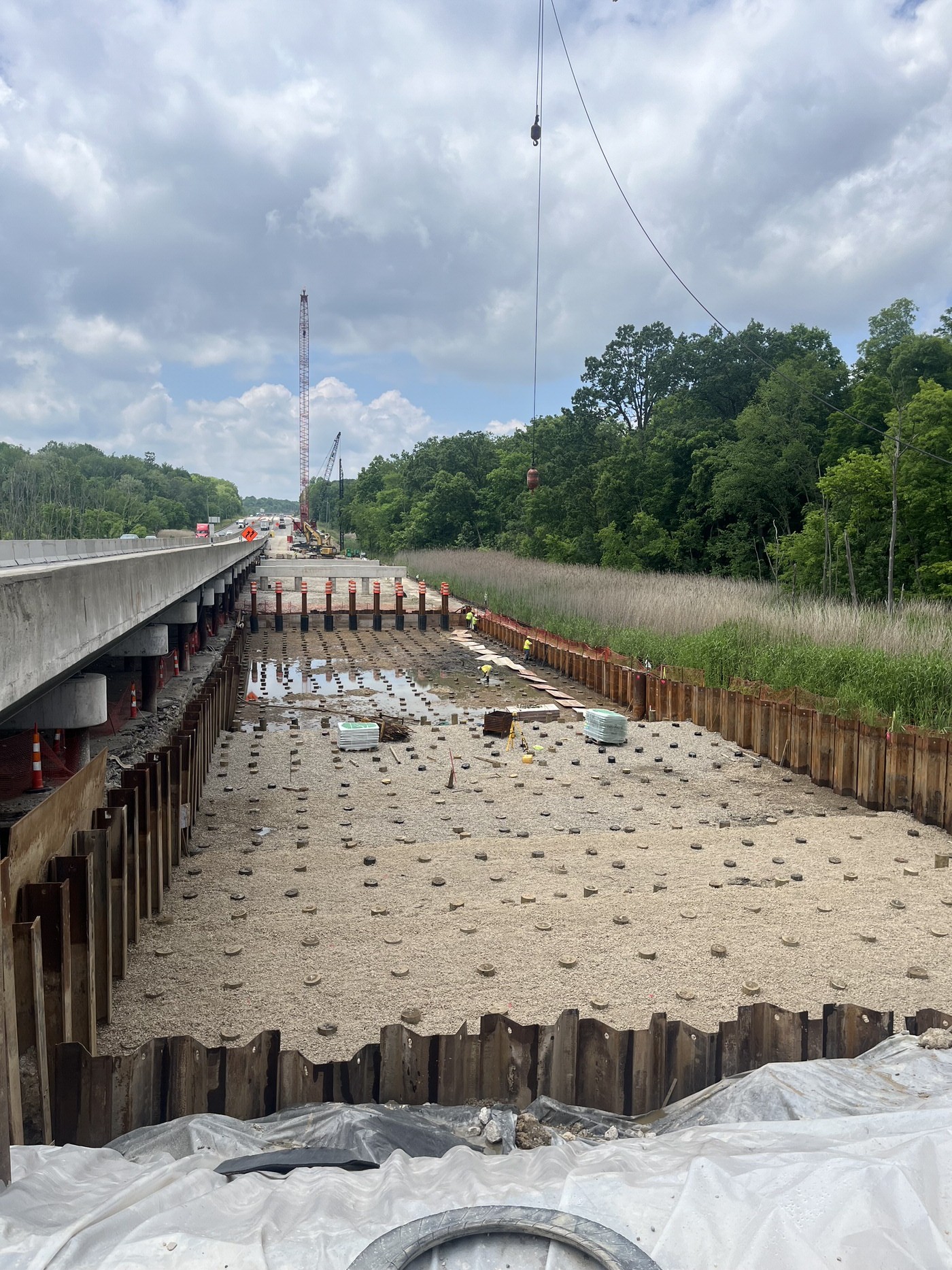 Workers constructing a load transfer platform over installed rigid inclusions beside a bridge.